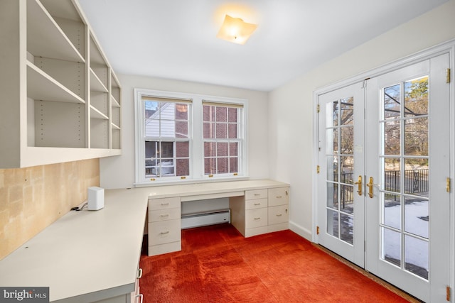 unfurnished office featuring a healthy amount of sunlight, built in desk, baseboard heating, and french doors