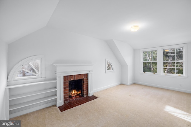 unfurnished living room with lofted ceiling, a brick fireplace, light colored carpet, and a healthy amount of sunlight