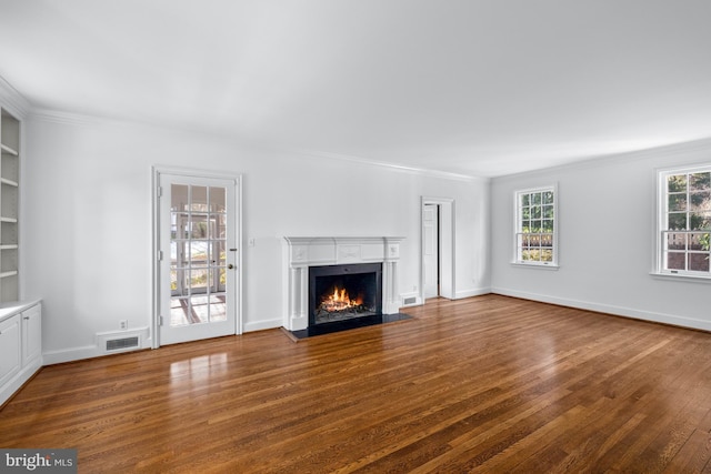 unfurnished living room featuring dark hardwood / wood-style flooring, built in shelves, and ornamental molding