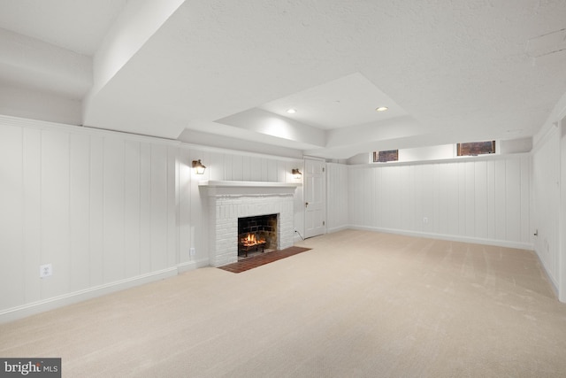 basement featuring light carpet, a brick fireplace, and a textured ceiling