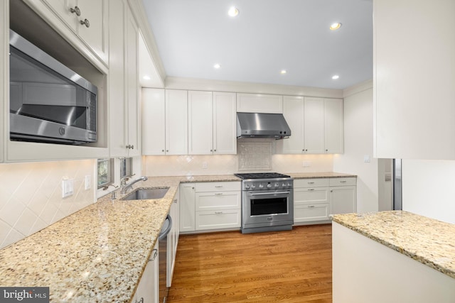 kitchen featuring sink, white cabinetry, stainless steel appliances, light stone countertops, and light wood-type flooring