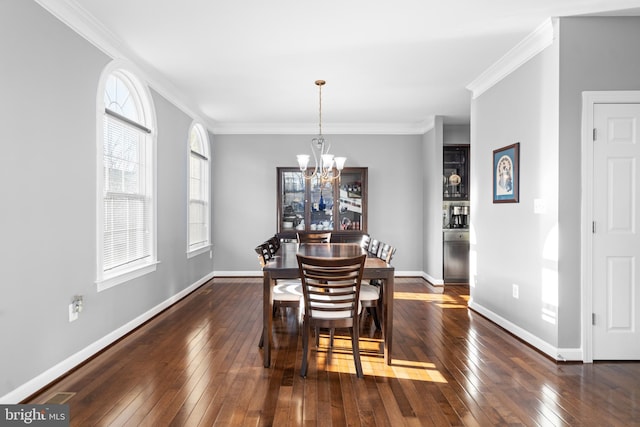 dining area with ornamental molding, dark wood-type flooring, and an inviting chandelier