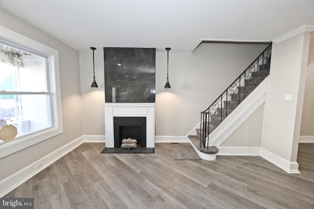 unfurnished living room with stairs, baseboards, a fireplace, and wood finished floors