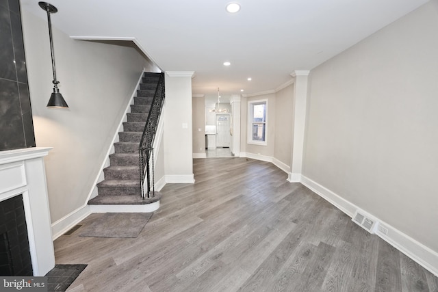 entrance foyer with stairs, ornamental molding, wood finished floors, and visible vents