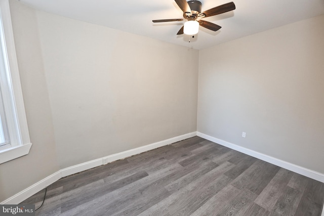 spare room with dark wood finished floors, a ceiling fan, and baseboards