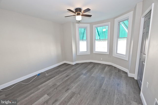 empty room featuring dark wood-style floors, ceiling fan, and baseboards