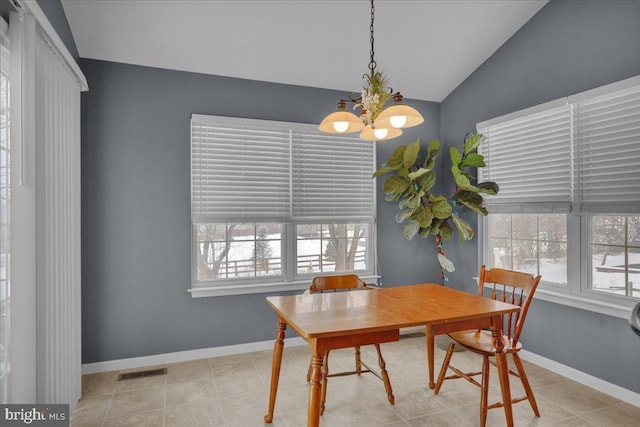 dining room featuring lofted ceiling, a wealth of natural light, a chandelier, and light tile patterned flooring