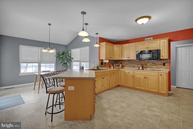 kitchen featuring hanging light fixtures, sink, light brown cabinets, and kitchen peninsula