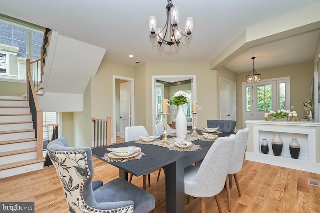 dining area with light wood-type flooring and a notable chandelier