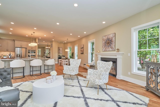 living room featuring a wealth of natural light, a chandelier, and light wood-type flooring