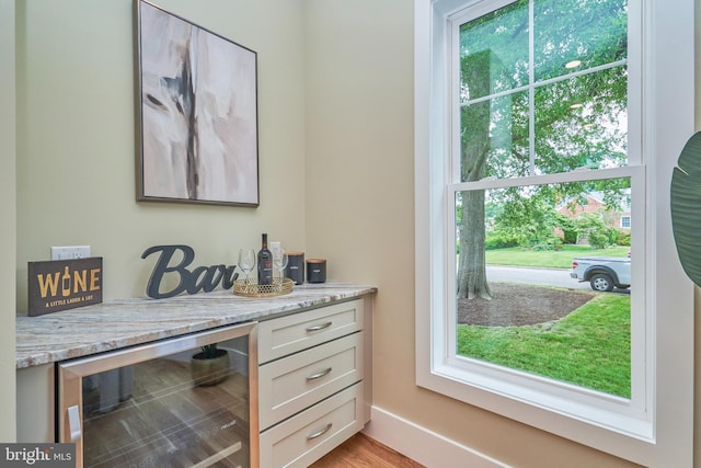 interior space with white cabinetry, beverage cooler, and light stone countertops