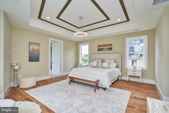 bedroom with hardwood / wood-style floors and a tray ceiling