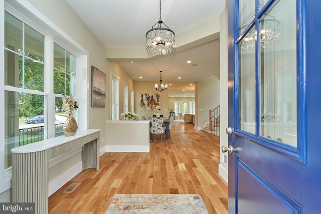 foyer featuring light wood-type flooring and a chandelier