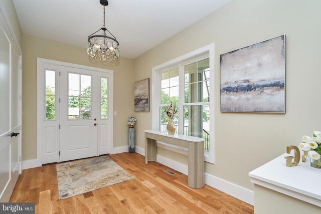 doorway to outside with light hardwood / wood-style flooring and a notable chandelier