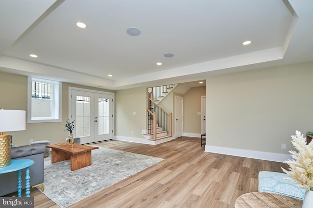 interior space featuring a tray ceiling, light hardwood / wood-style flooring, and french doors