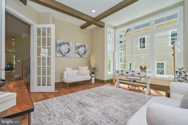 living area featuring hardwood / wood-style floors, beam ceiling, and french doors