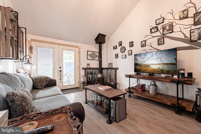 living room featuring french doors, lofted ceiling, light hardwood / wood-style flooring, and a wood stove