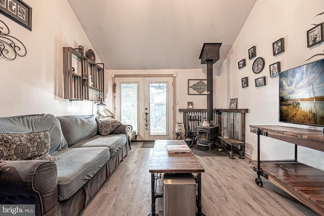 living room with french doors, vaulted ceiling, hardwood / wood-style floors, and a wood stove