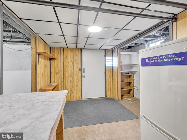 basement with a paneled ceiling and wooden walls