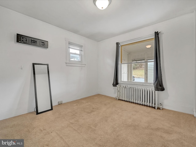 empty room featuring light carpet and radiator heating unit