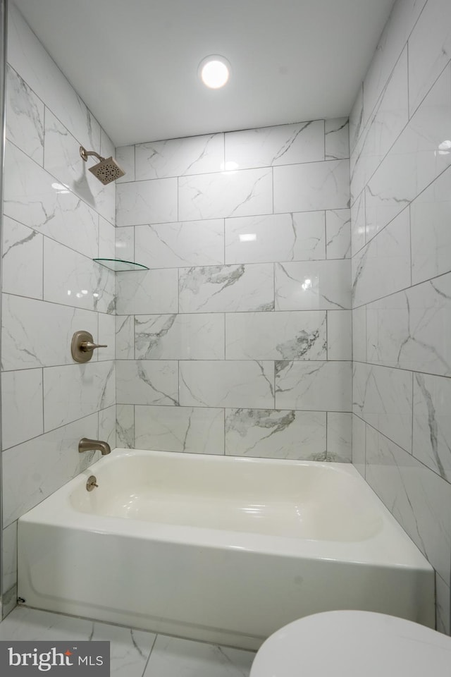 bathroom featuring toilet and tiled shower / bath combo