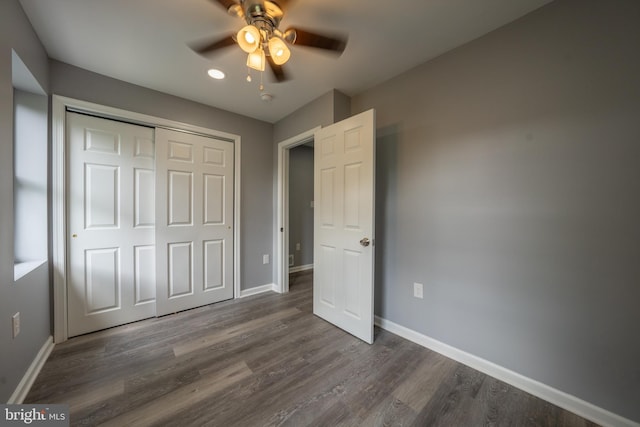 unfurnished bedroom with dark wood-type flooring, ceiling fan, and a closet