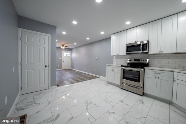 kitchen featuring ceiling fan, decorative backsplash, white cabinets, and appliances with stainless steel finishes