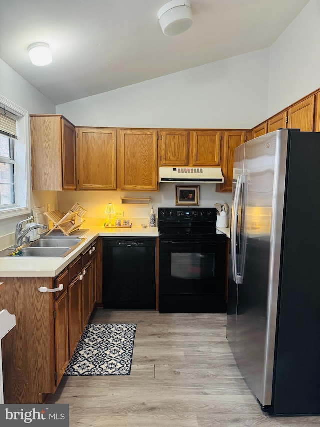 kitchen featuring lofted ceiling, light hardwood / wood-style floors, sink, and black appliances