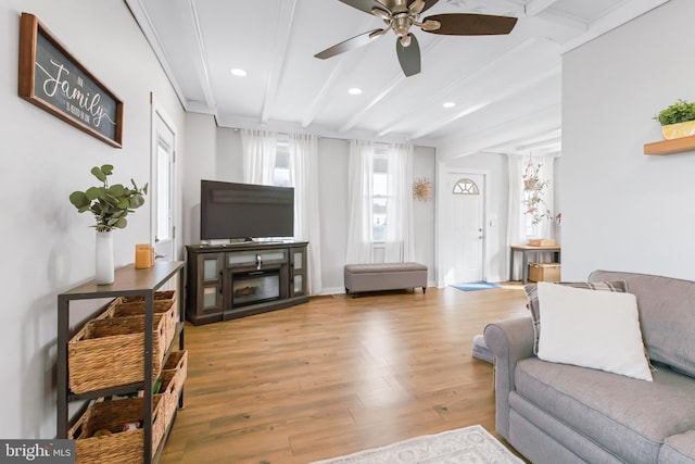 living room with ceiling fan, wood-type flooring, and beamed ceiling