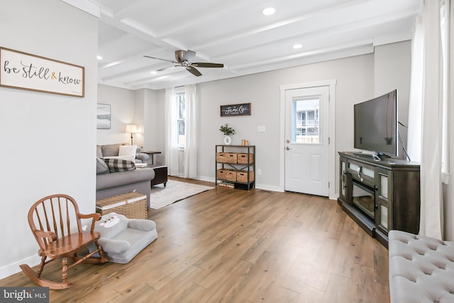 living room featuring beamed ceiling, wood-type flooring, a wealth of natural light, and ceiling fan