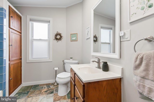 bathroom with crown molding, a healthy amount of sunlight, toilet, and vanity