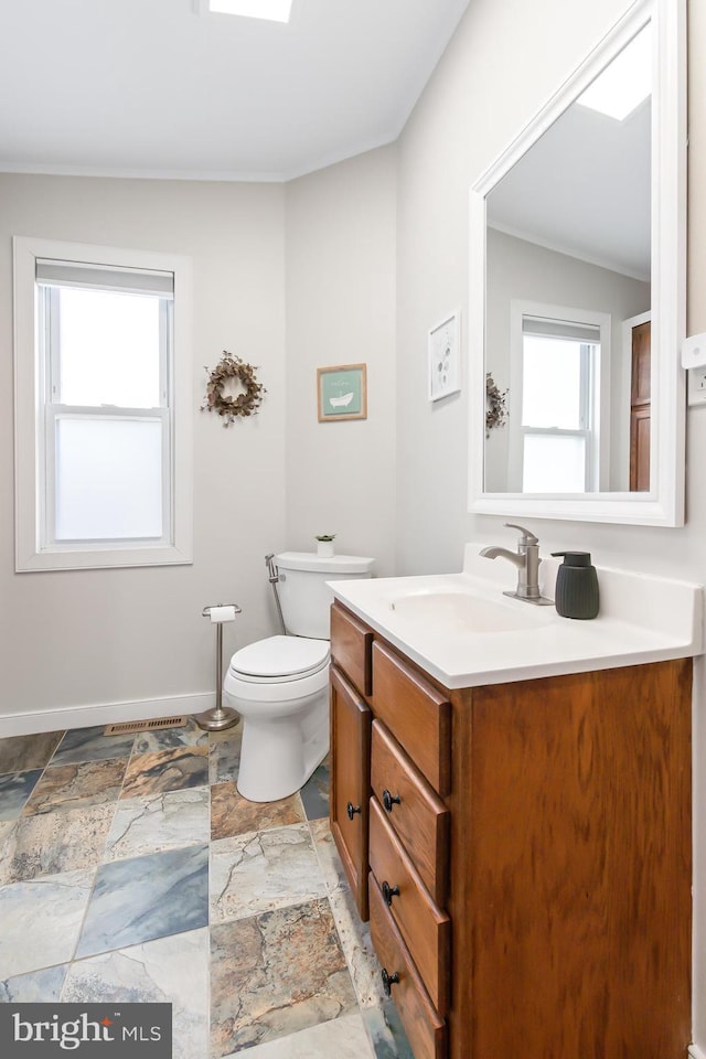 bathroom with ornamental molding, plenty of natural light, toilet, and vanity