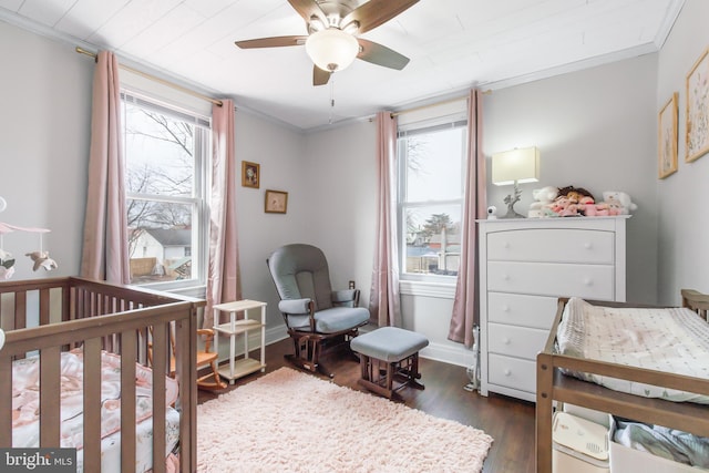 bedroom with a crib, ornamental molding, and multiple windows