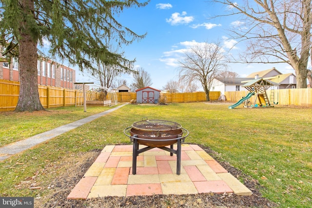 view of yard with a playground, a patio area, a shed, and a fire pit