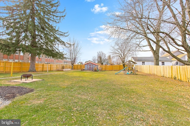 view of yard featuring a storage shed, a fire pit, and a playground