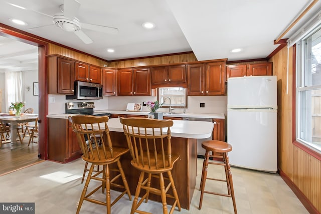 kitchen featuring a kitchen island, sink, a kitchen bar, ceiling fan, and stainless steel appliances