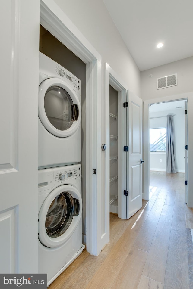 washroom with stacked washer and dryer and light wood-type flooring