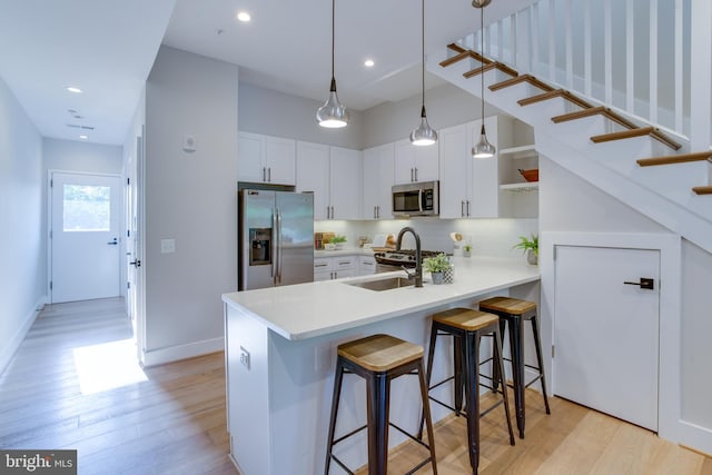 kitchen featuring sink, stainless steel appliances, white cabinets, a kitchen bar, and kitchen peninsula