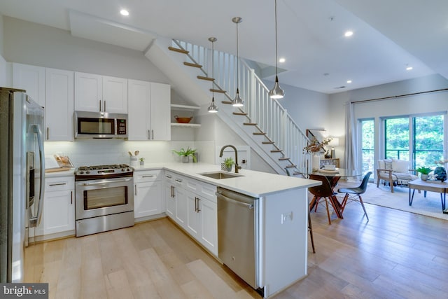 kitchen with appliances with stainless steel finishes, pendant lighting, white cabinetry, sink, and kitchen peninsula