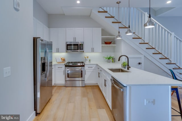 kitchen featuring appliances with stainless steel finishes, pendant lighting, sink, white cabinets, and kitchen peninsula