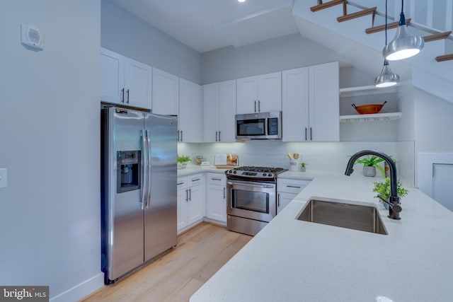 kitchen with appliances with stainless steel finishes, tasteful backsplash, white cabinetry, sink, and hanging light fixtures