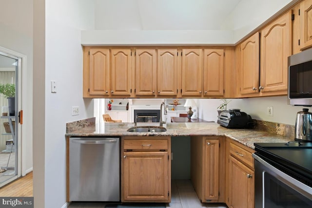 kitchen featuring appliances with stainless steel finishes, light stone countertops, and sink