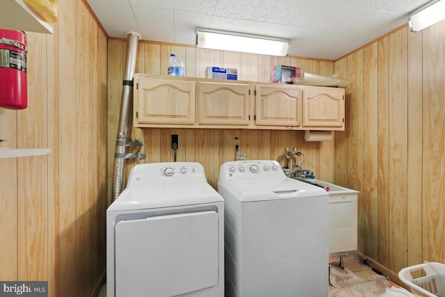 laundry area featuring cabinets, washer and dryer, and wood walls