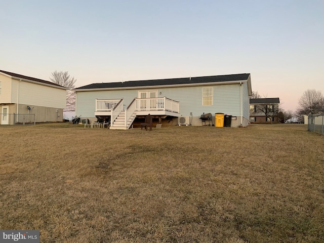 back house at dusk with a wooden deck and a yard