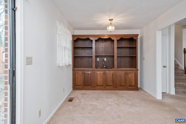 unfurnished dining area with light carpet and a notable chandelier