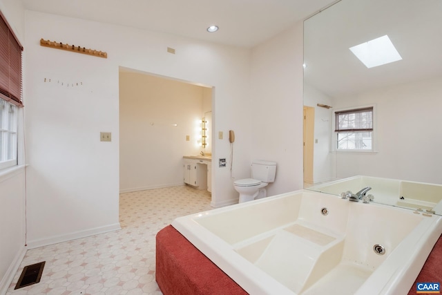 bathroom with vanity, a bath, lofted ceiling with skylight, and toilet