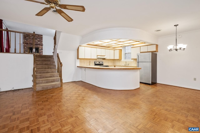 unfurnished living room featuring ceiling fan with notable chandelier, ornamental molding, and light parquet flooring