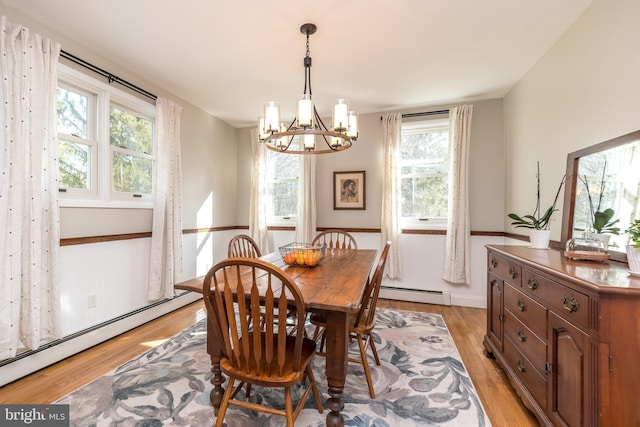 dining space with a baseboard heating unit, a chandelier, and light wood-type flooring