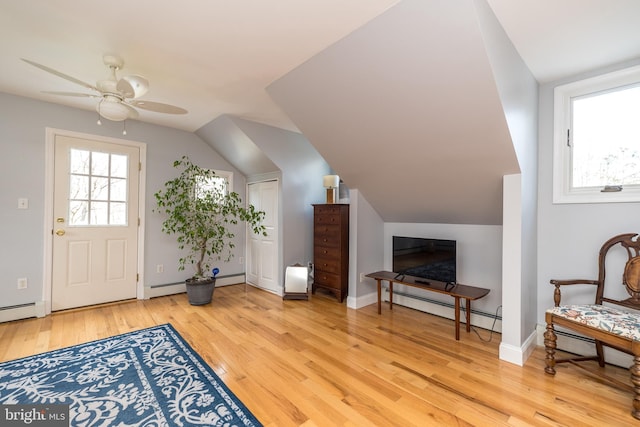 living area featuring lofted ceiling, baseboard heating, and light hardwood / wood-style floors