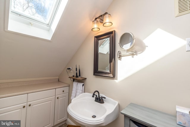 bathroom with sink and vaulted ceiling with skylight